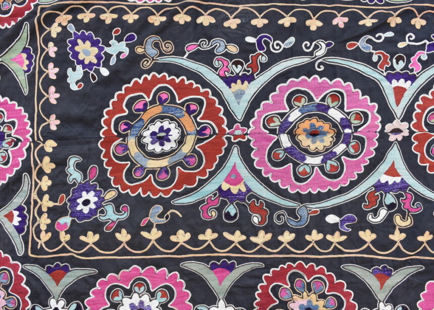 Embroidered panel or SUZANI, with flowery rosette motifs in bright pink and red on black background. T