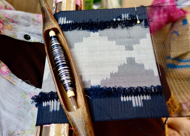Piece of cloth on the loom, with navy blue and white ikat patterning, Vientiane, Laos.