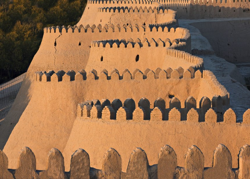 Zig-zag and crenallated walls of Khiva's old city glow in the sunset.