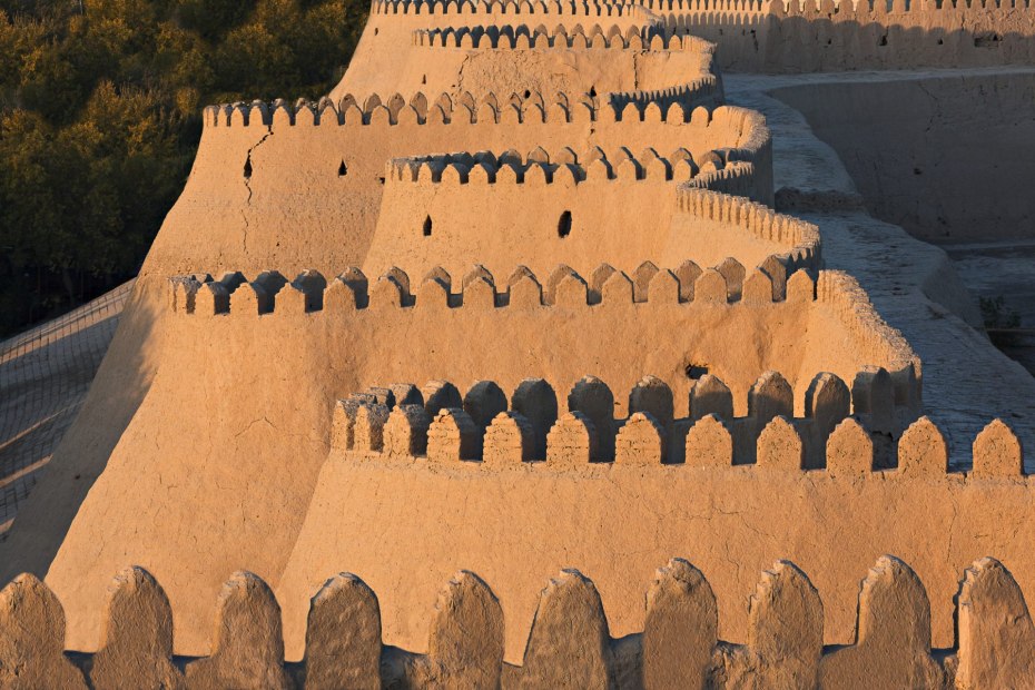 Zig-zag and crenallated walls of Khiva's old city glow in the sunset.