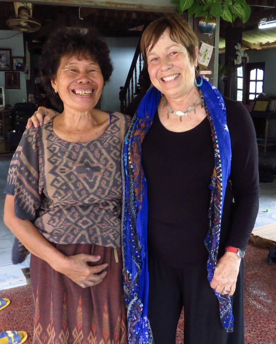 Two women stand together, one wearing hand-woven indigo dyed ikat fabric.