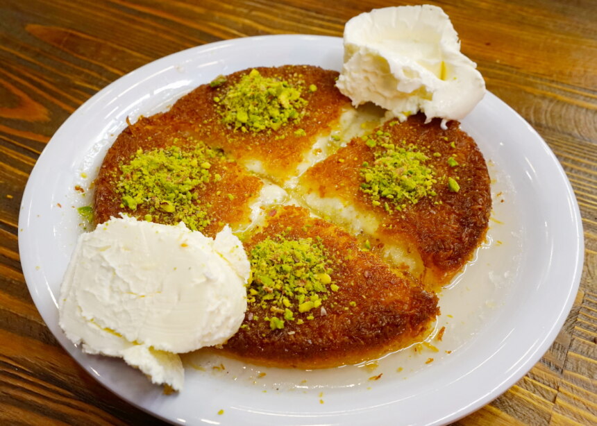 Round baked dessert called Kunefe, made of shredded wheat topped with pistachios.