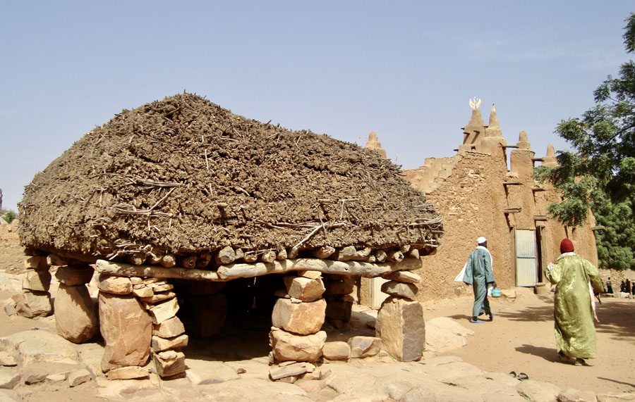 Open structure with rock supports and thcik thatch roof.