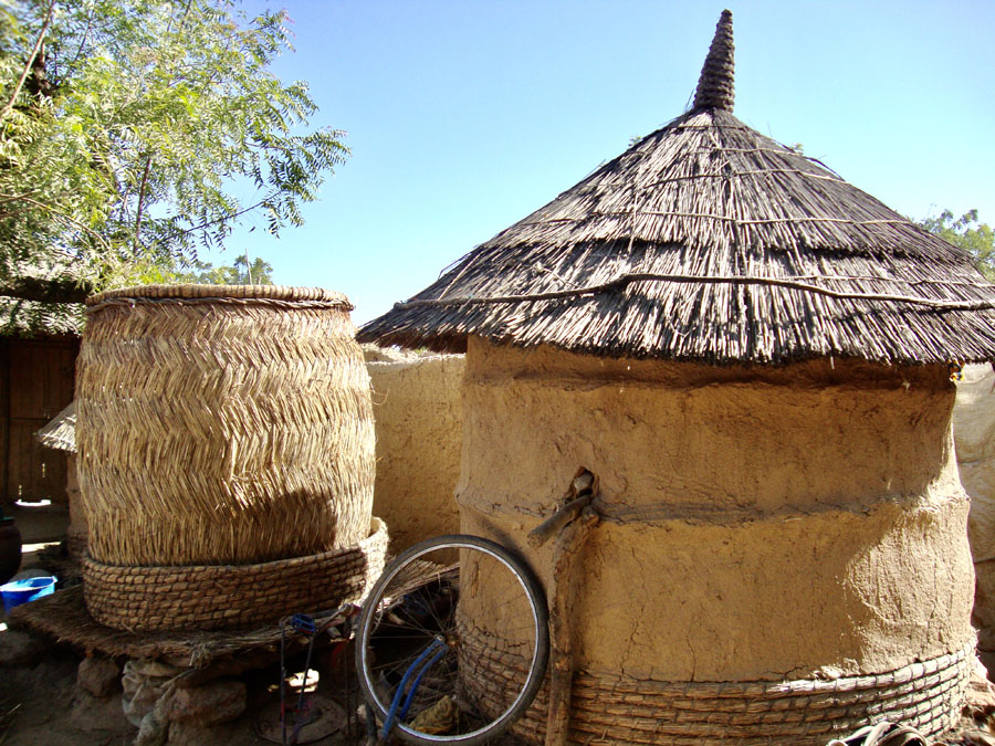 One completed mud granary and second one under construction at left; Mali.