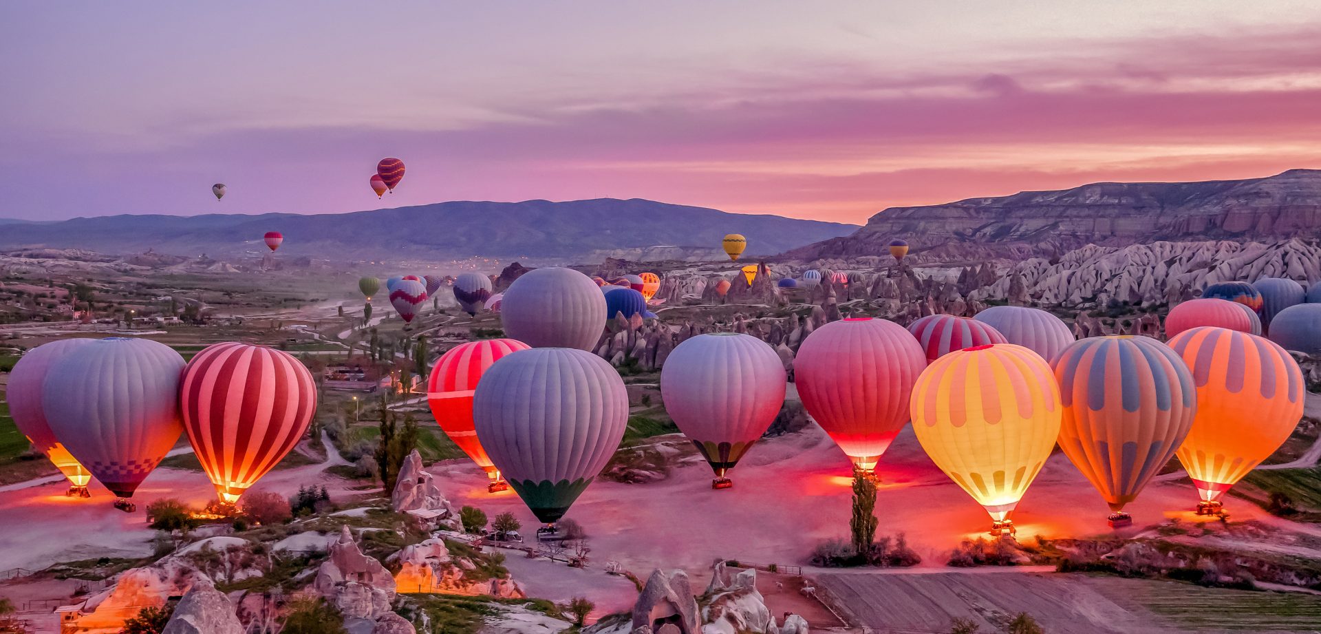 Hot air balloons glow in the early morning light of Cappadocia, Turkey.