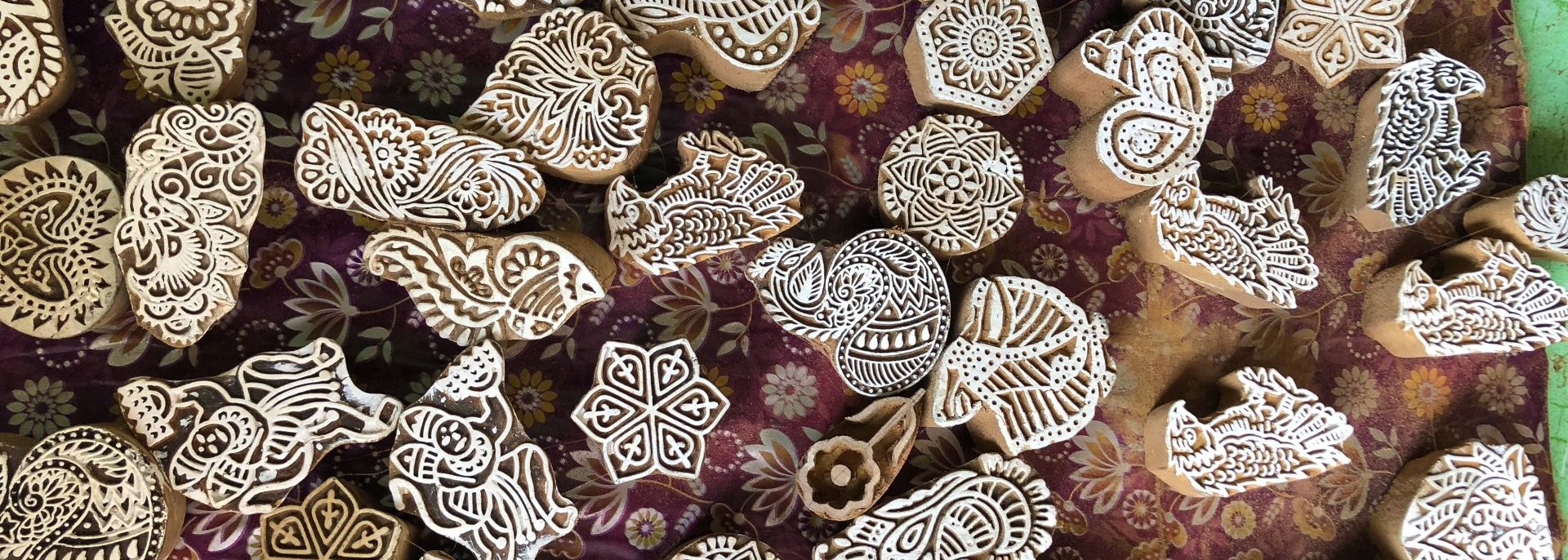 Small wood blocks for stamping cloth, with different designs of flowers, animals, paisleys and mandalas.