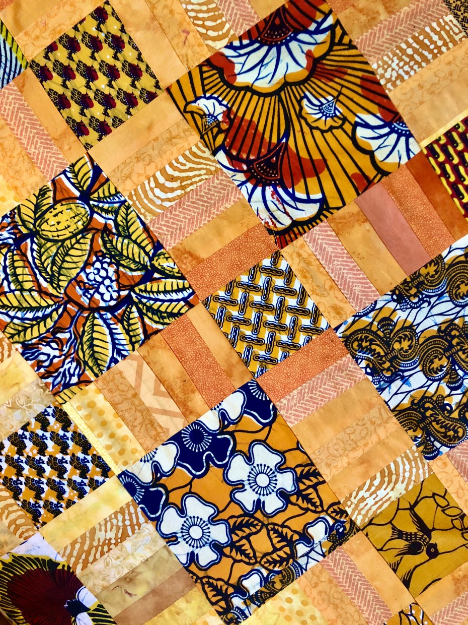 Detail of top end of quilt with printed fabrics from Ghana and Indonesian cotton batik cloth strips; by Cynthia Samaké.
