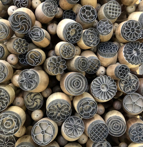 Dozens of bread stamps made of thin metal rods hammered into wooden handles in decorative patterns, used to mark raw dough.