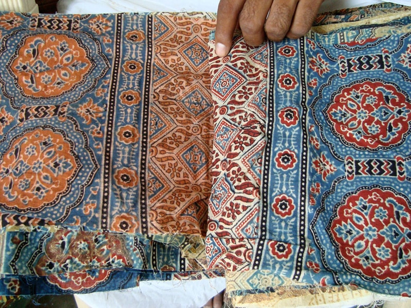 Sample fabrics dyed with different resists and natural dyes, in blue and rust colors.