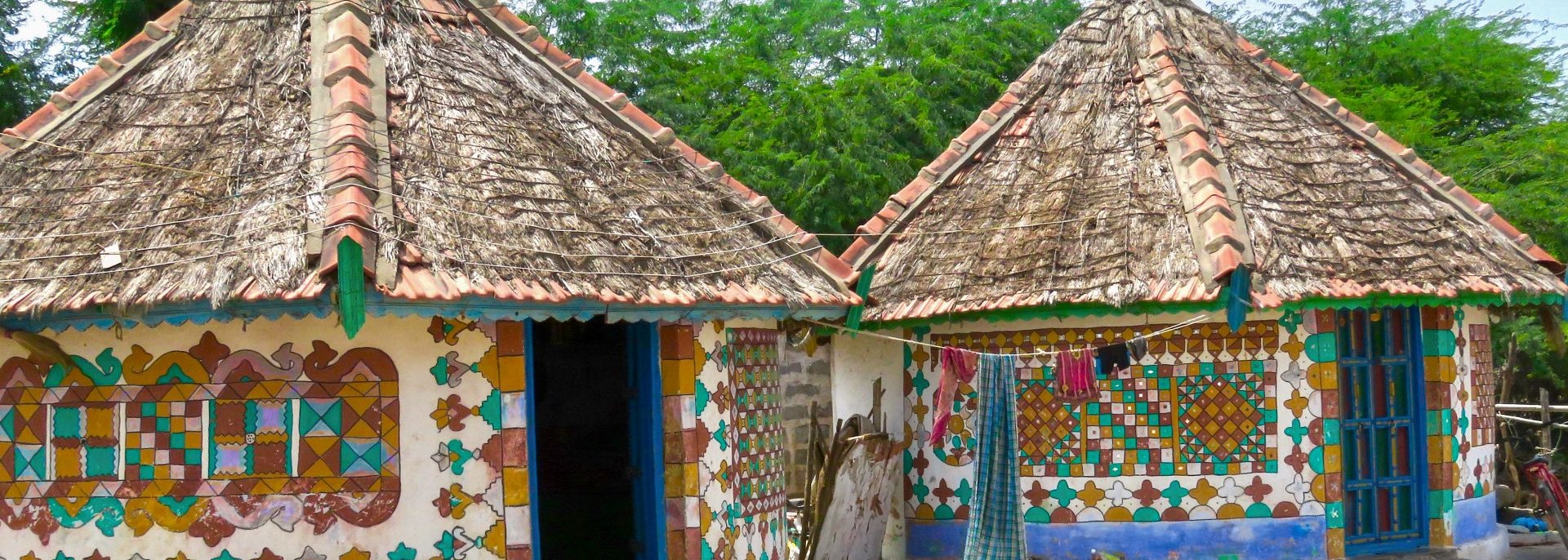 Decorated mud bungalows with painted patterns on the walls.