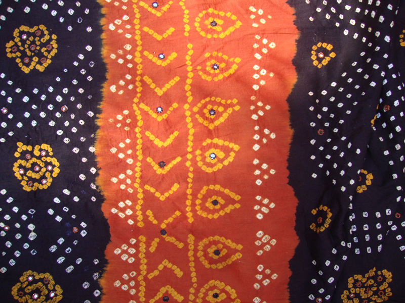 Detail of and orange, yellow and brown silk tie-dyed scarf in the bandhini method.