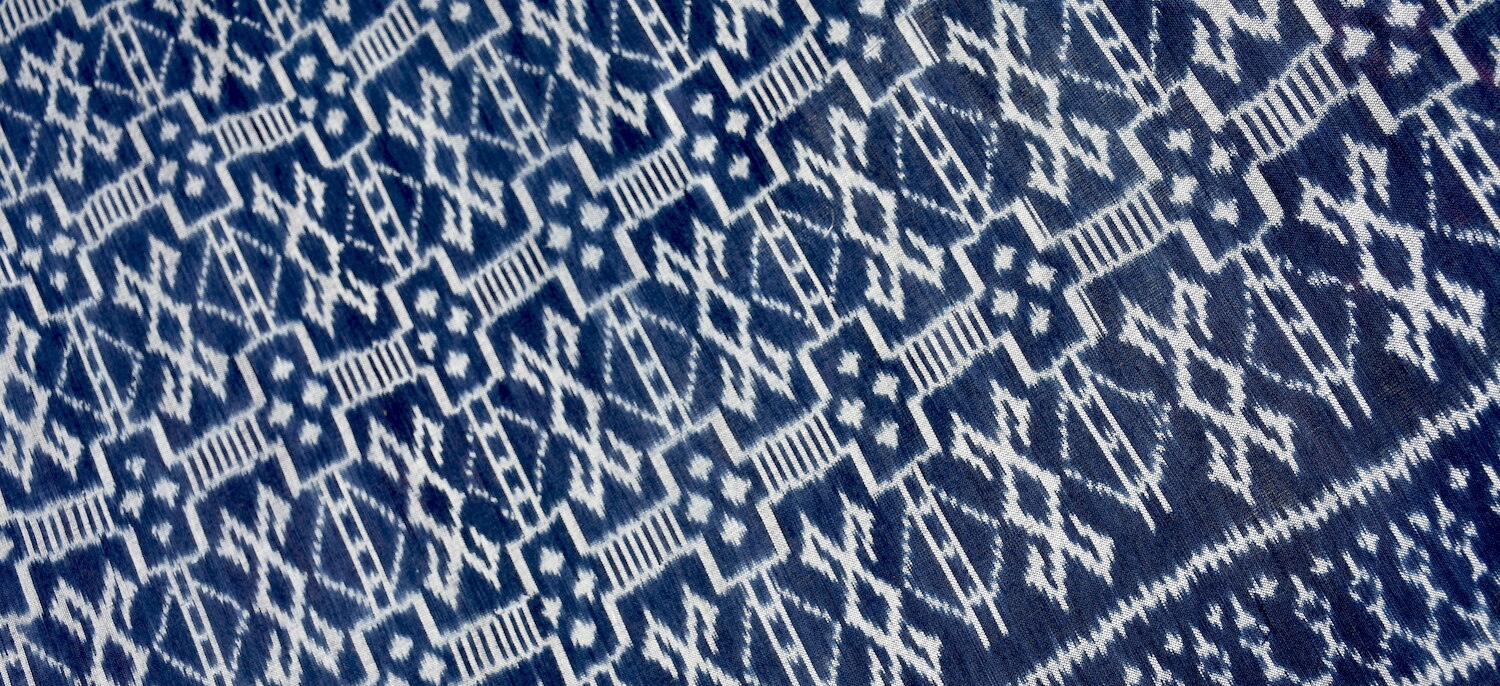 Detail view of hand woven indigo ikat cotton fabric with geometric patterns.