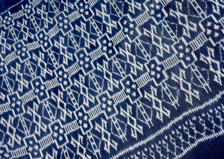 Detail view of hand woven indigo ikat cotton fabric with geometric patterns.