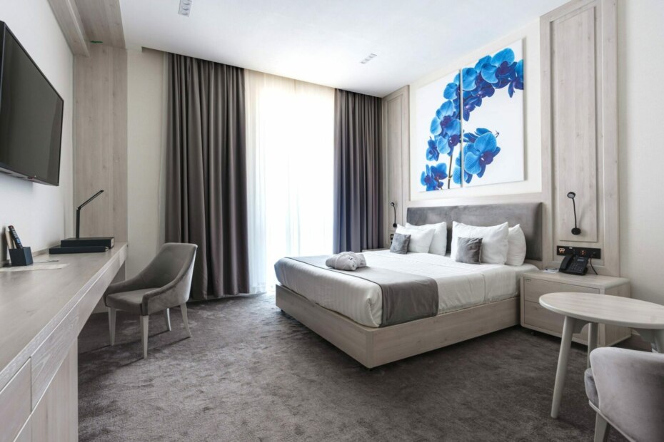 Modern hotel room with double bed and wall art.
