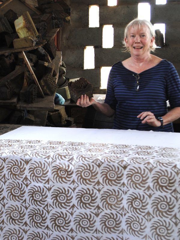 White woman printing cotton cloth with wax designs; Ghana