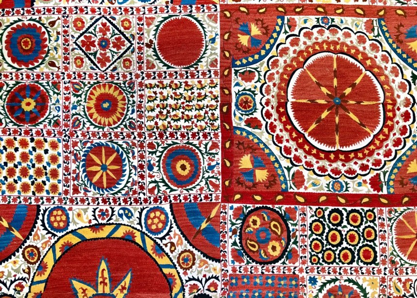 Red and white embroidered wall hanging or Suzani, with flower patterns.