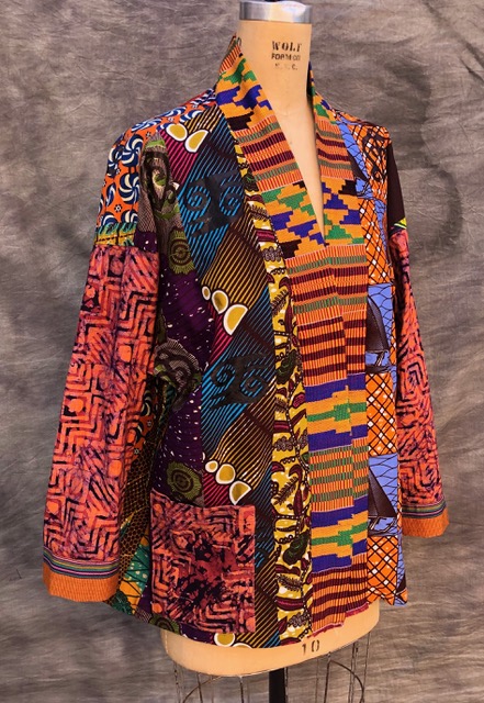 Traditional handwoven kente strips and printed cotton fabrics in patchwork jacket by Suzi Click.