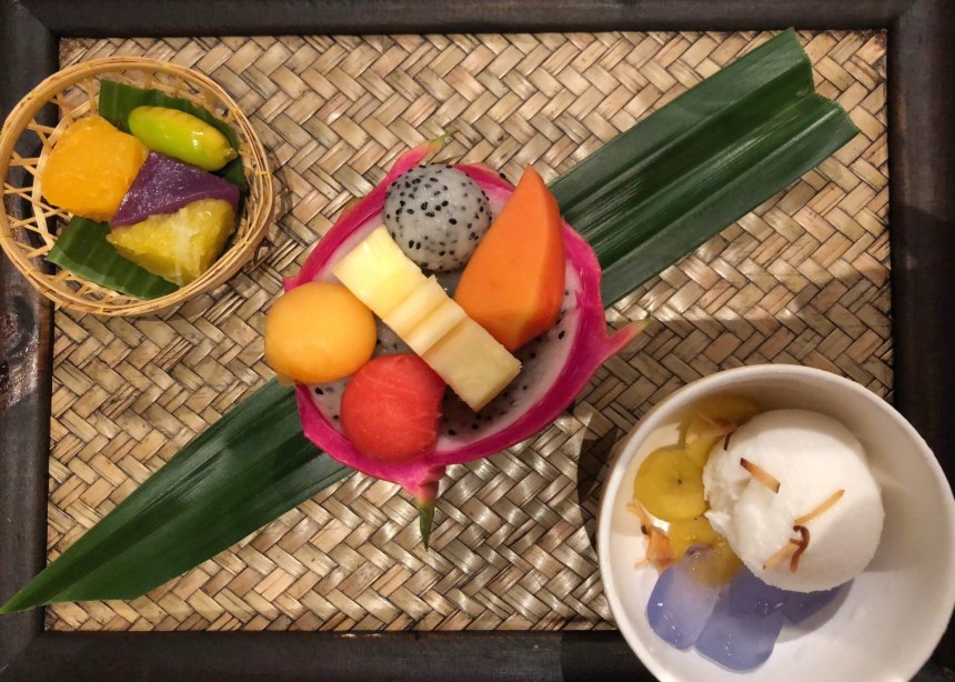 A dish of cut-up tropical fruits sits next to a dish of coconut ice cream, in Thailand.