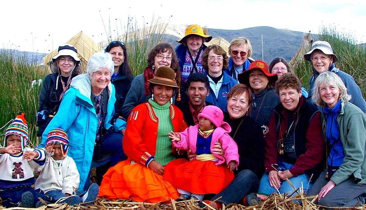 Behind the Scenes group on textile tour sit on reed Urus islands in Peru. 