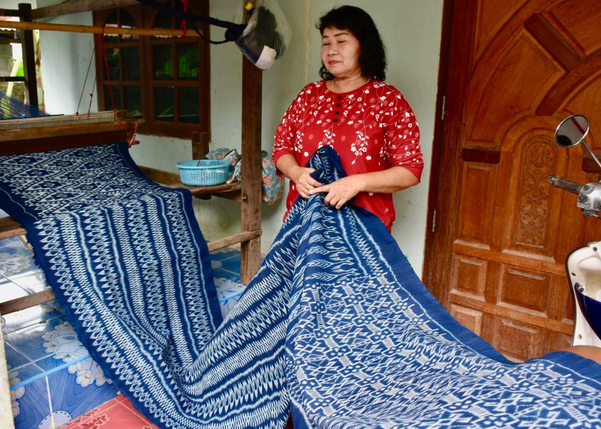 Woman stands by her indigo hand-woven cloth.